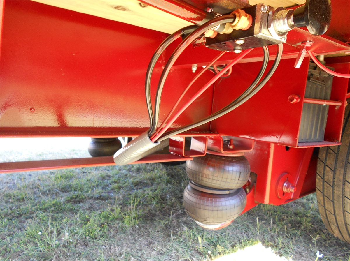 Close-up of the Air-Ride feature on the Red, 40 Foot, Pierced Frame, Lift Axle Trailer built by Custom Built Gooseneck Trailers